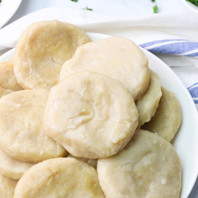 A plateful of Caribbiean Boiled dumplings with ackee and saltfish in the background