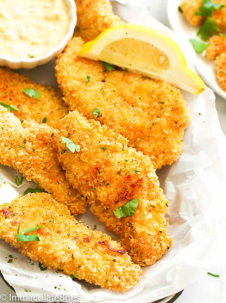 Crispy baked chicken tenders with lemon wedges