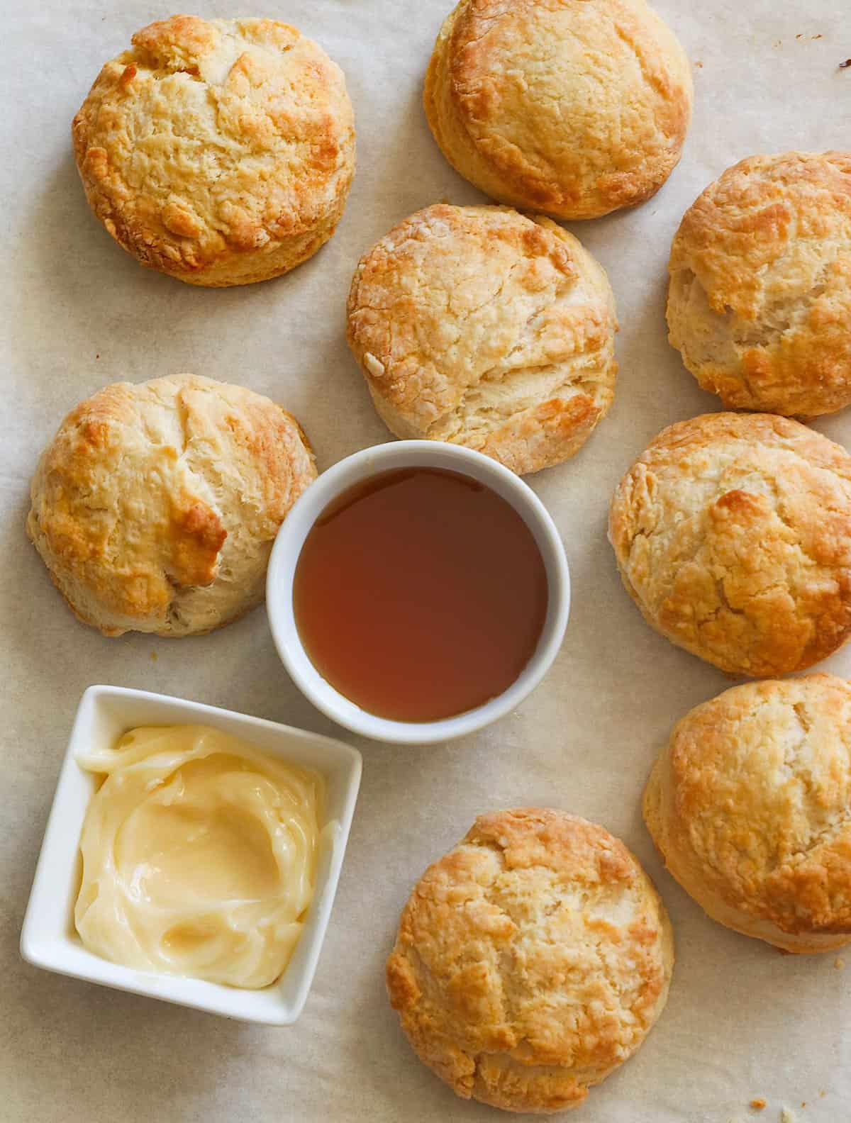 Insanely comforting Honey Butter Biscuits with honey butter and honey ready for drizzling