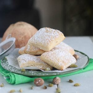 Diving into a plateful of soft baked mandazi dusted with powdered sugar for an insanely delicious treat