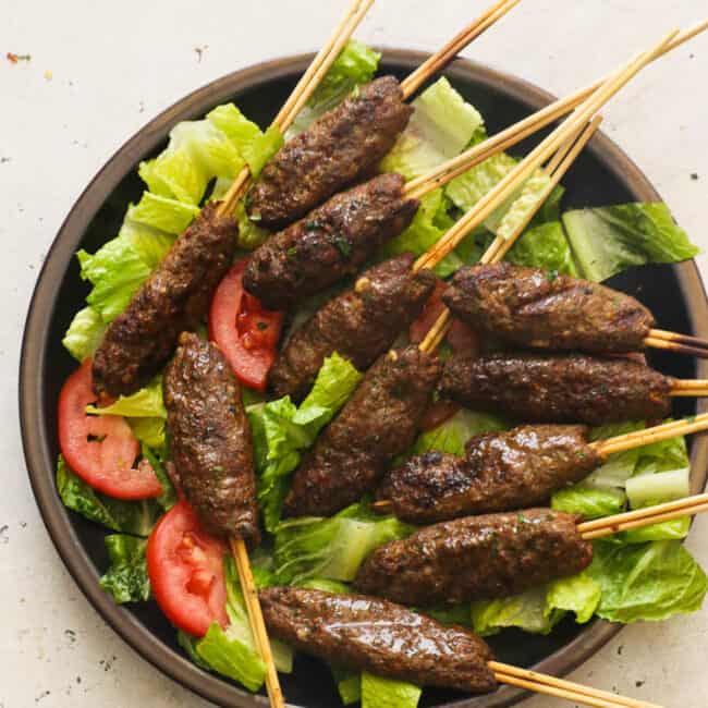 Kofta Kabob on a skewer over lettuce and tomatoes