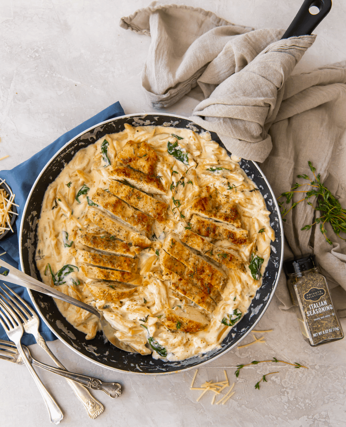 Chicken on a bed of pasta and alfredo sauce in a black pan